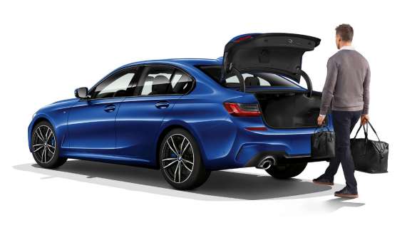 BMW 3 Series Sedan, automatic tailgate operation. Three-quarter rear shot of standing BMW 3 Series Sedan with driver automatically opening the tailgate with his foot.