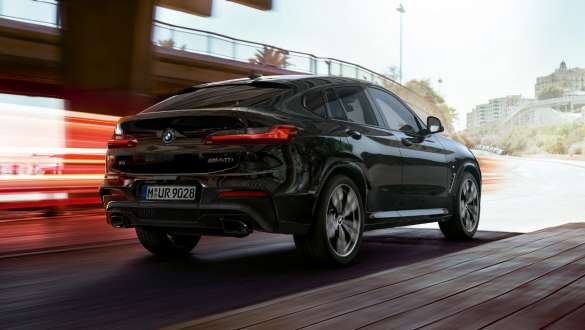 BMW X4 M40i three-quarter rear view. BMW X4 M40i in Black Sapphire metallic, driving, exterior, three-quarter rear view with light strips.