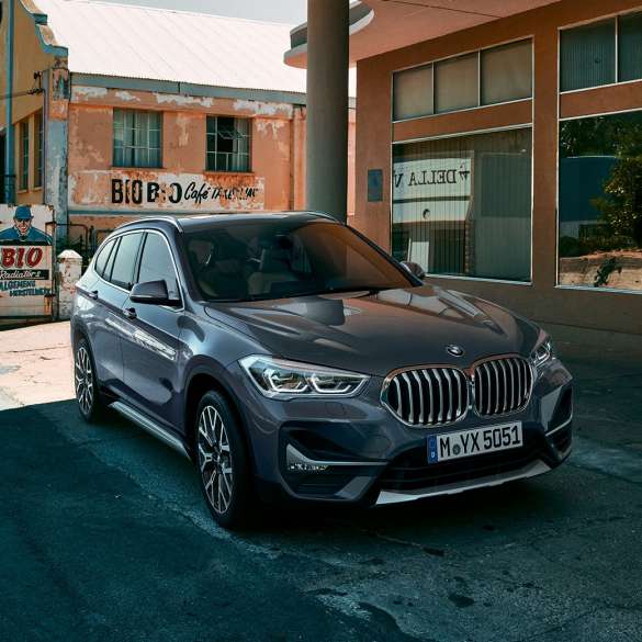 BMW X1, three-quarter front view. BMW X1, three-quarter front view standing in front of urban scenery.