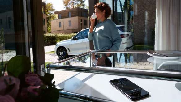 Remote Software Upgrade BMW X5 Woman drinking a cup of coffee while she updates the software of her BMW X5 via Remote Software Upgrade G05 2018