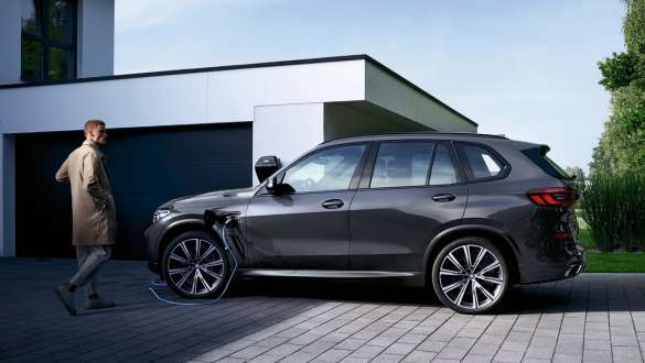 Plug-in hybrid BMW X5 xDrive45e G05 side view in front of garage Plug-in hybrid BMW X5 xDrive45e G05 side view in front of garage with model