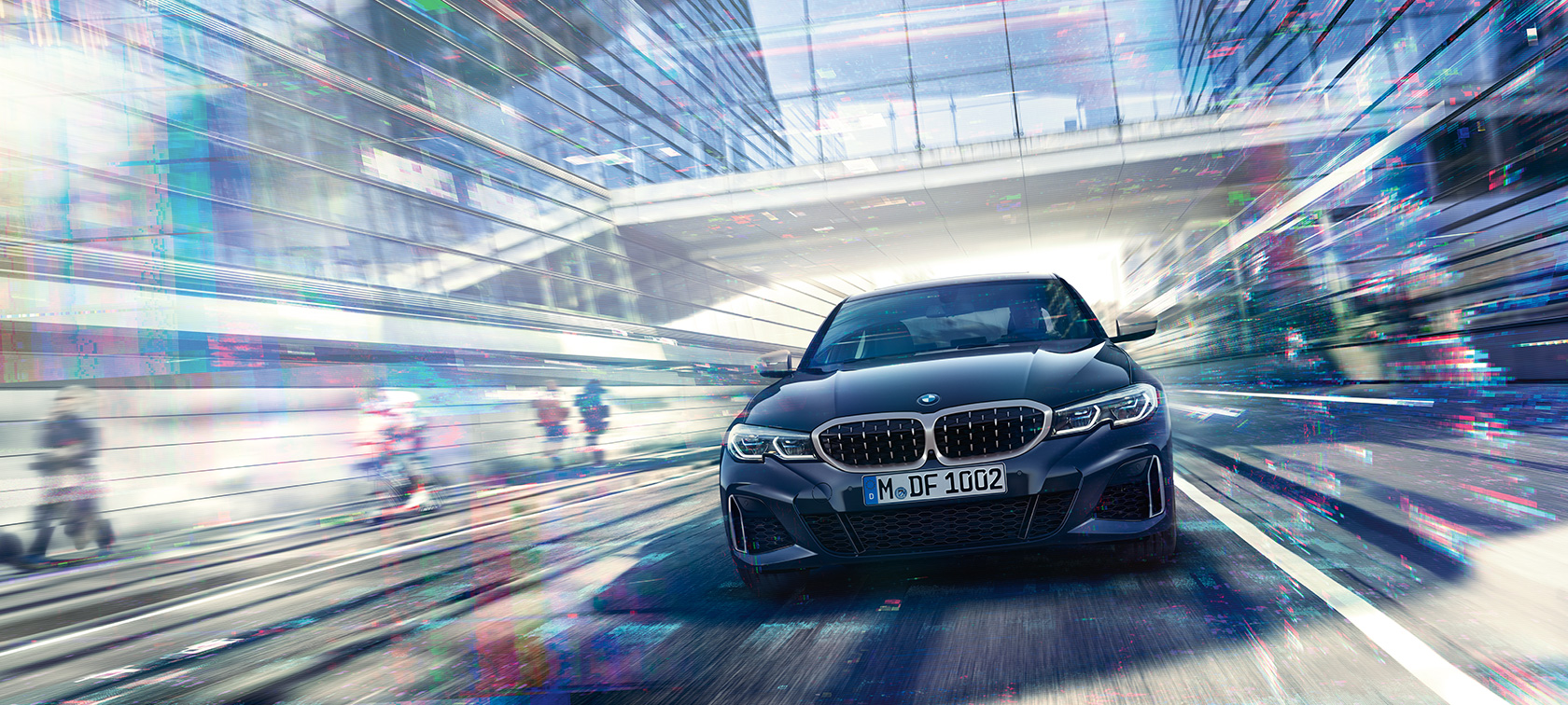 BMW 3 Series Sedan, frontal view BMW M340i xDrive. Frontal view of the driving BMW M340i xDrive Sedan between urban glass buildings.