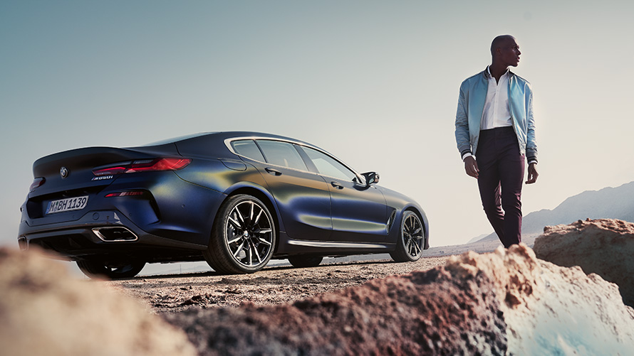 BMW 8 Series Gran Coupé G16 LCI Facelift three-quarter rear view with male model low-angle shot BMW 8 Series Gran Coupé G16 LCI Facelift three-quarter rear view with male model low-angle shot