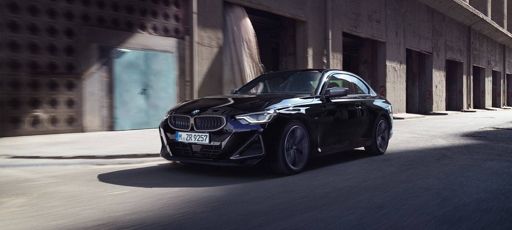 BMW M240i xDrive Coupé G42 2021 Black Sapphire metallic three-quarter front view driving 