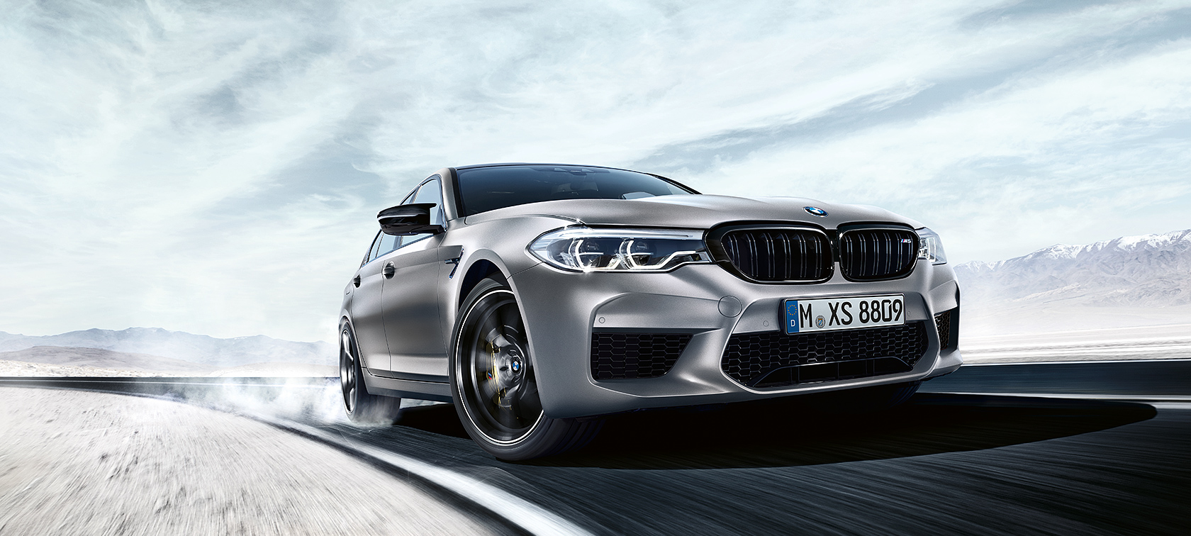 BMW M5 Competition in action Grey BMW M5 Competition driving on highway in front of desert landscape