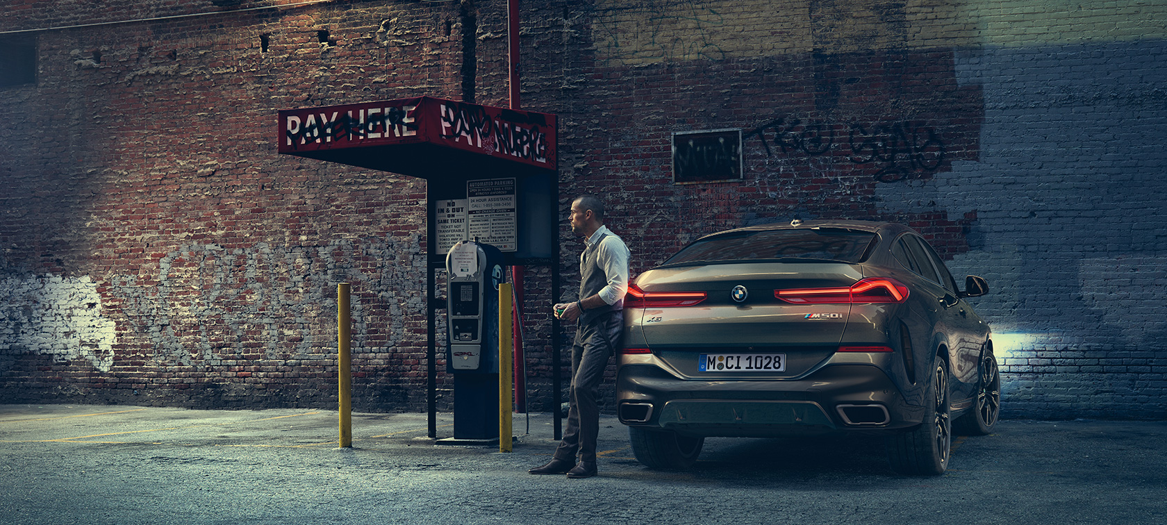 Rear of BMW X6 M50i. Man leaning on rear of the BMW X6 M50i.