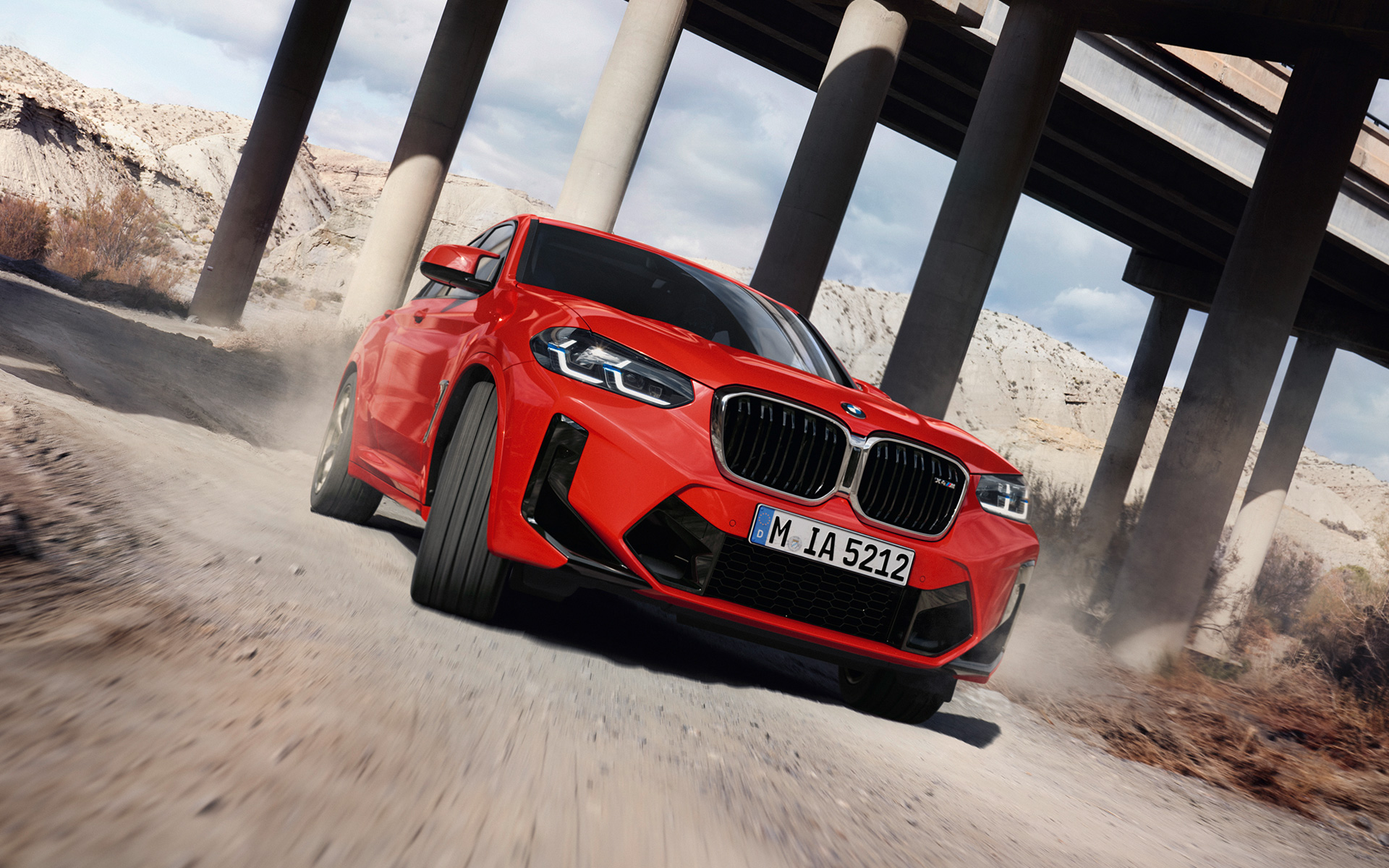 BMW X4 M F98 LCI Facelift 2021 Toronto Red metallic three-quarter front view in front of bridge columns