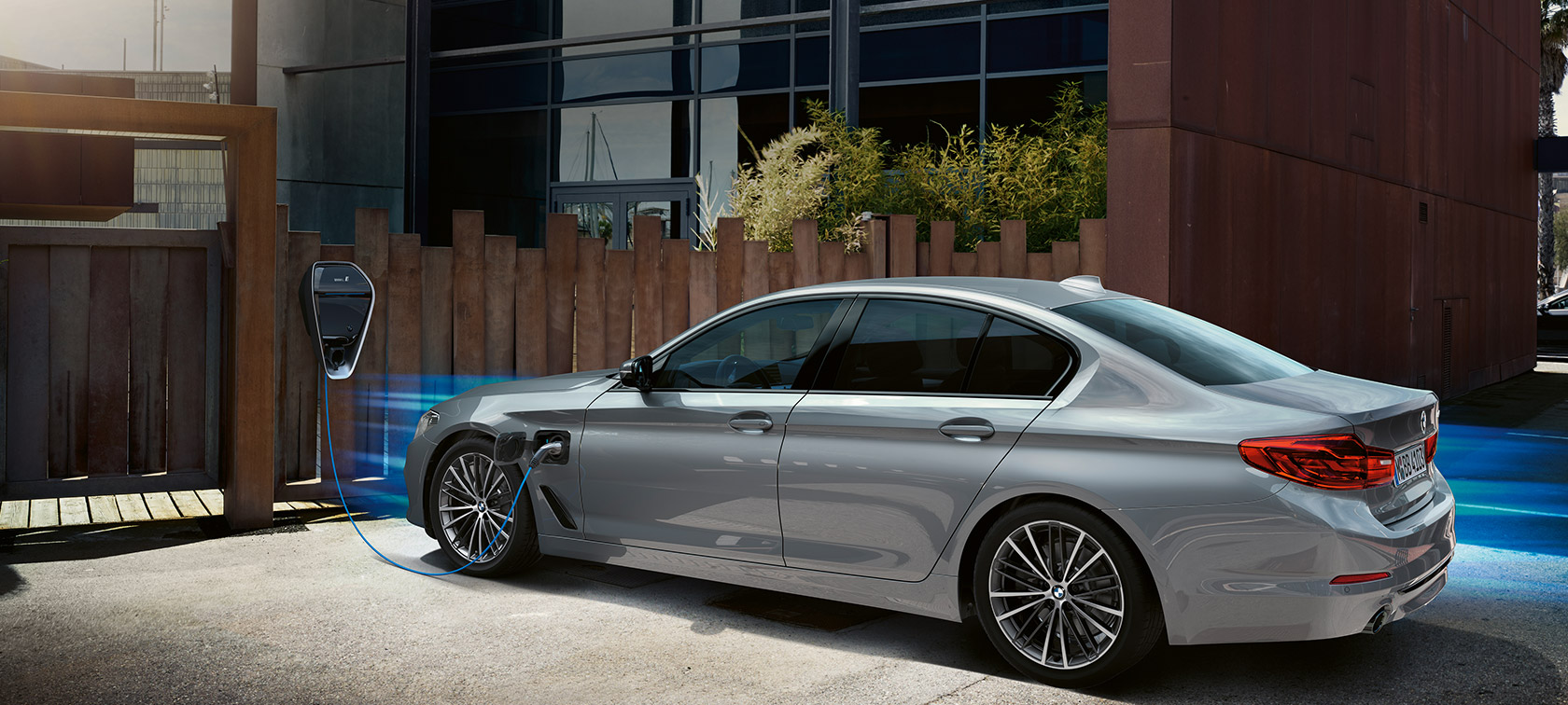 BMW 530e at charging station. BMW 530e in three-quarter rear view at charging station.