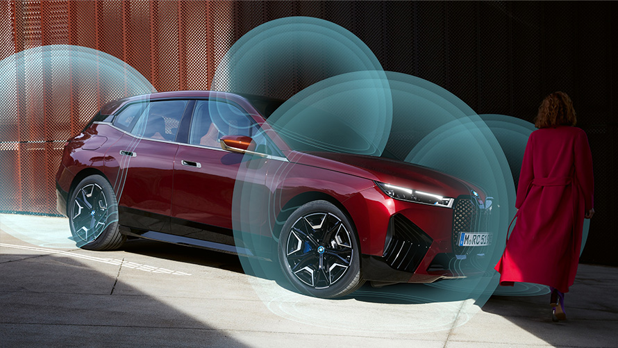 BMW Digital Keys Woman in red coat in front of BMW iX (i20) in three-quarter view with visualised location radar