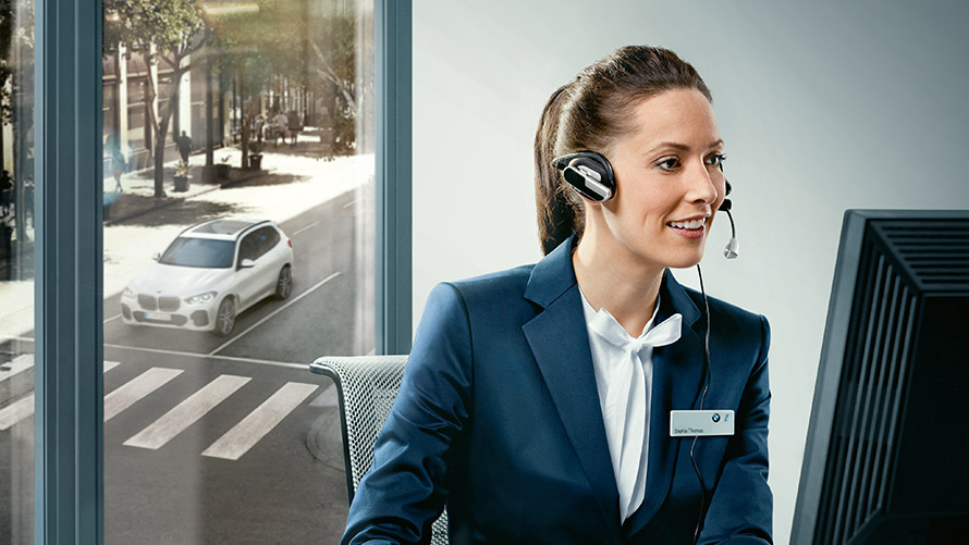 Concierge Services Concierge Services: BMW employee sitting at her desk wearing headset