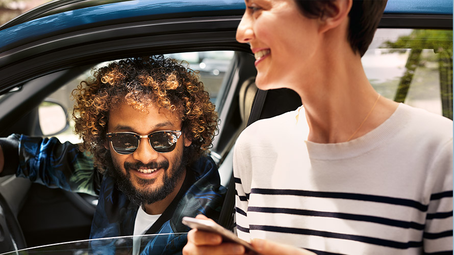 My BMW App Man in BMW and woman outside the BMW using the My BMW App on smartphone