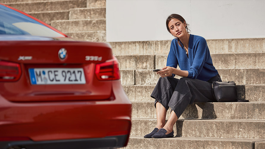 Service & Breakdown Assistance Woman sitting in front of her BMW and uses Service & Breakdown Assistance