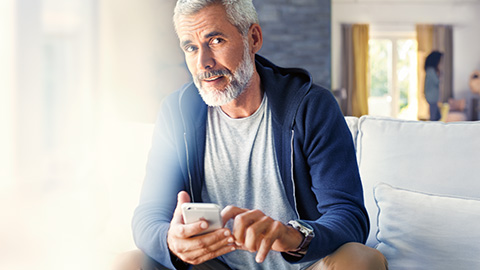 BMW ConectedDrive Store Man with smartphone sitting on sofa BMW ConectedDrive Store Man with smartphone sitting on sofa