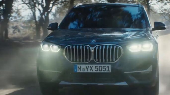 BMW X1, three-quarter front view. BMW X1, three-quarter front view driving in front nature scenery.